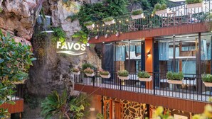 A modern hotel with a rock facade, outdoor seating, and a waterfall feature. - Favos Ninh Binh Hotel & Villas (Nam Hoa Lu)