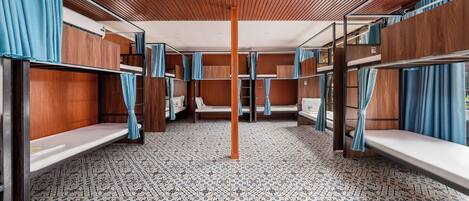 A train compartment with bunk beds, wooden paneling, and patterned floor tiles.
