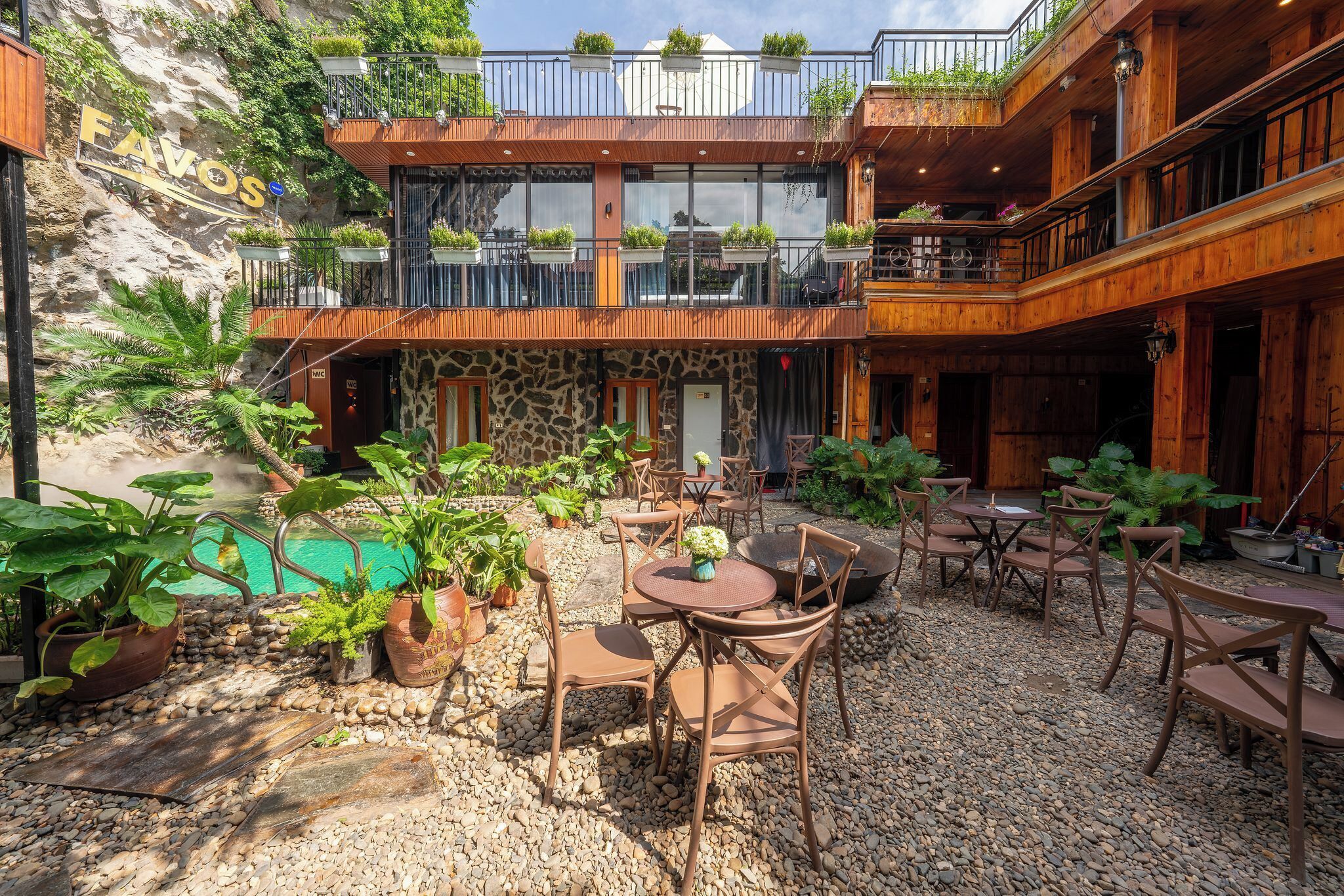 A courtyard with outdoor seating, a pool, and a building with balconies.