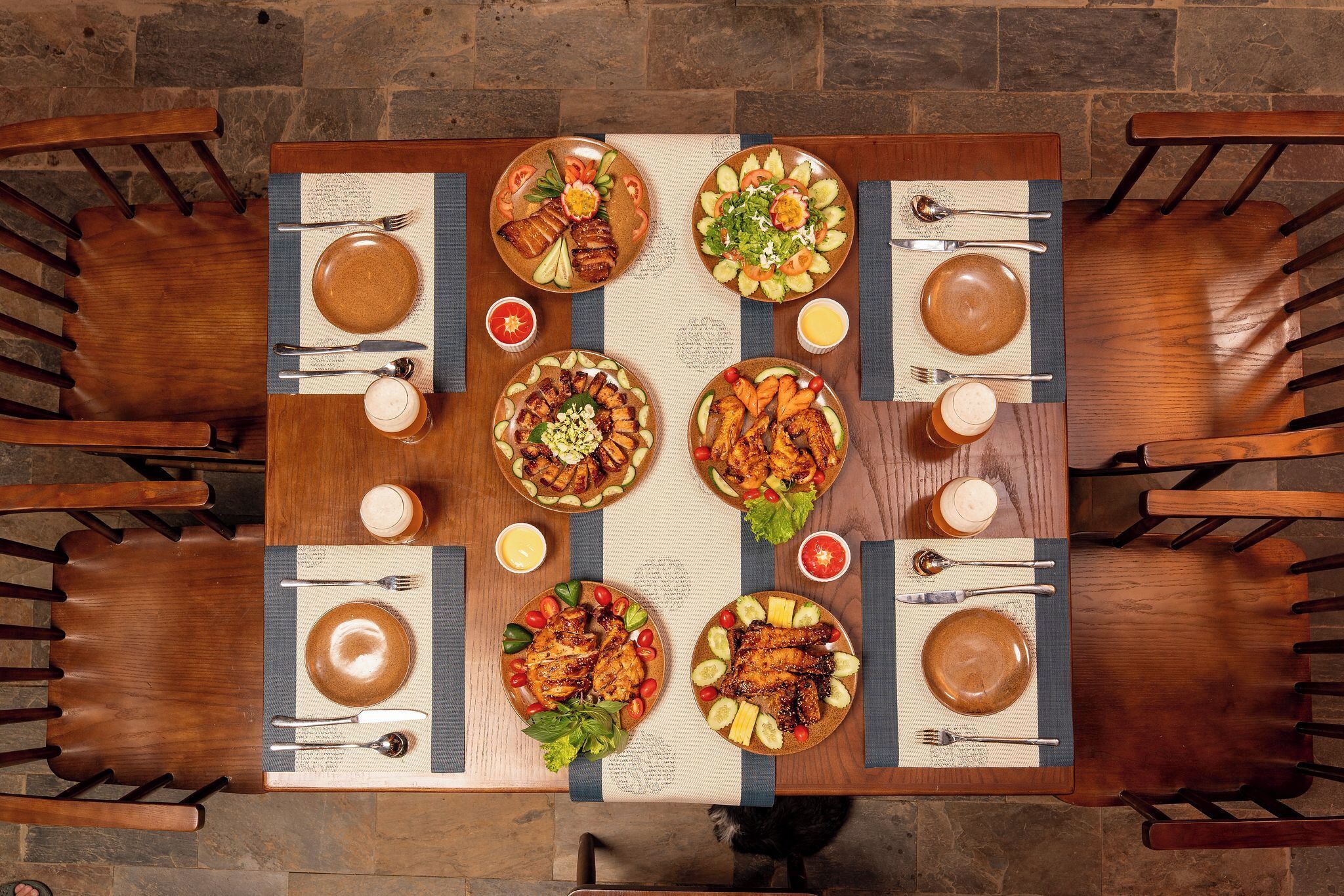 A dining table set for four with plates of food, cutlery, and glasses.