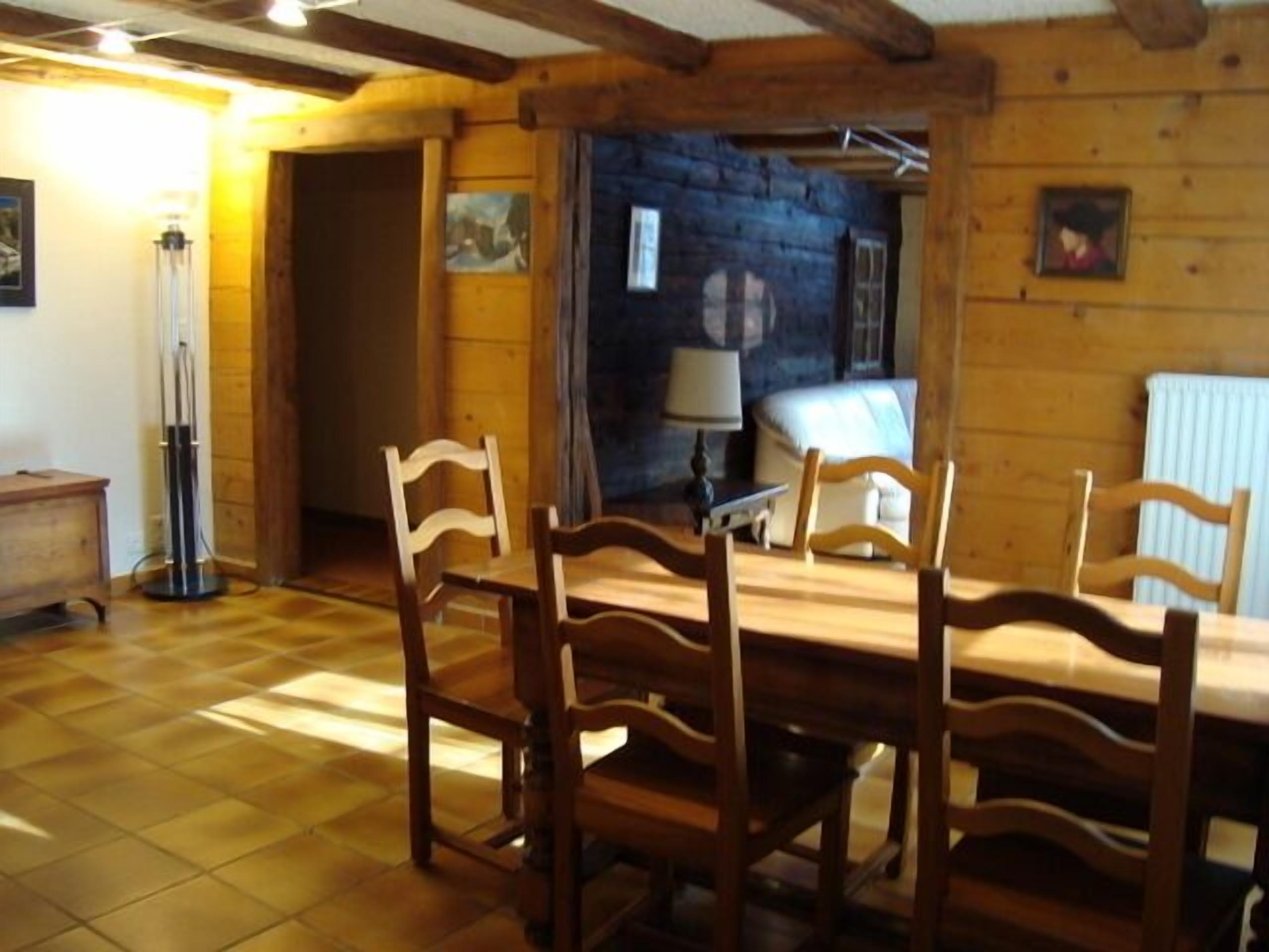 Ein Holzespeisesaal mit sechs Stühlen in einem Raum mit freiliegenden Balken und Holzwänden.