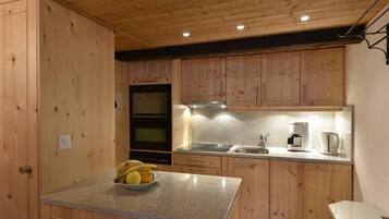 Une cuisine avec des meubles en bois, des plans de travail en granit, une cuisinière et une machine à café.