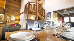 A dining area with a wooden staircase, a table set for a meal, and a view of the upper floor. - Chalet Jean - Grimentz - Beautiful traditional Swiss chalet for 2 to 12 people<br>Luxury 3-storey chal (Grimentz)