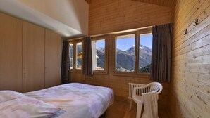 Un dormitorio con cama, radiador y vistas a montañas a través de amplios ventanales.