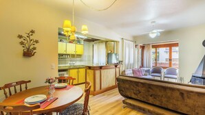 Un'area pranzo con un tavolo e sedie in legno, un divano e una cucina sullo sfondo.