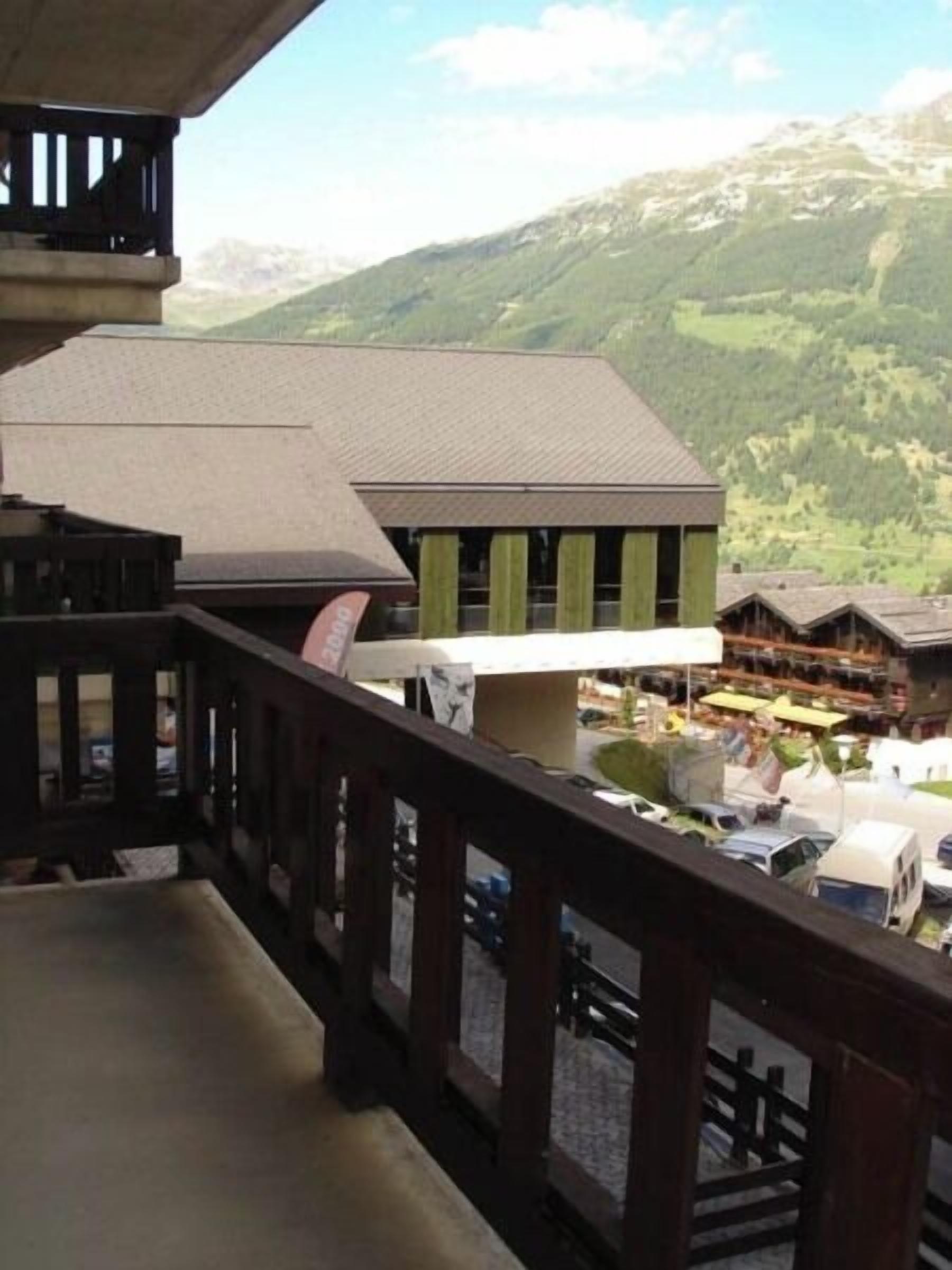 Blick vom Balkon auf eine gebirgige Landschaft mit einem Gebäude mit Holzfassade und einem Schild.