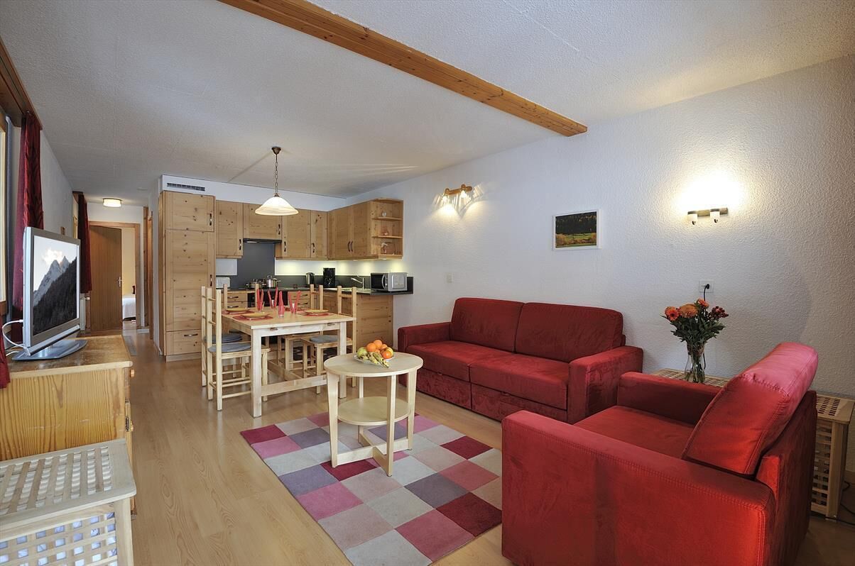 A compact living space with a kitchen, dining area, and a red sofa.