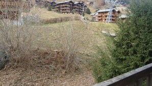 A mountain lodge with multiple wooden buildings, a ski lift, and a forested hillside. - Comfortable 3-room apartment for 4-6 persons : Living room with double sofa-bed - 1 room with 2 beds (Grimentz)