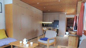 Een gezellige kamer met houten meubels, een eettafel en een keuken in de achtergrond.