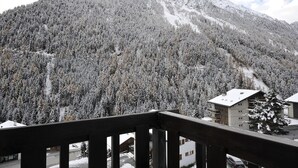 Berglandschap met met sneeuw bedekte bomen en een gebouw met balkon op de voorgrond.
