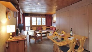 Een gezellige kamer met houten meubels, een eettafel en een televisie.