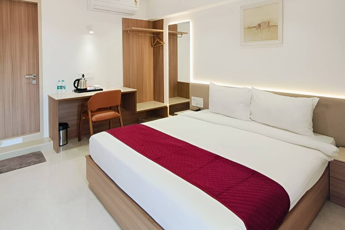 Una habitación de hotel moderna con una cama grande, un escritorio, una silla y un armario.