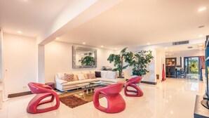 A modern living room with a white sofa, a glass coffee table, and red chairs. - Townhouse With Ocean View Puerto Bahia P5 (Las Terrenas)