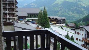 A mountain resort with a view of the valley, including a building with a balcony and a parking area. - 2-room apartment for 4 persons : Living room with 2 sofa-beds - 1 room with 2 beds - kitchen with fi (Grimentz)
