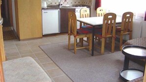 A compact kitchen with a refrigerator, a sink, and a dining area with a table and chairs. - 2-room apartment for 4 persons : Living room with 2 sofa-beds - 1 room with 2 beds - kitchen with fi (Grimentz)