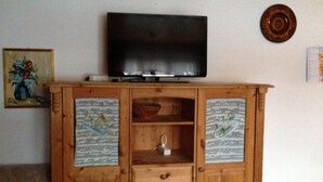 A wooden entertainment center with a flat-screen TV on top, two shelves with decorative papers, and a small table at the bottom. - 2-room apartment for 4 persons : Living room with 2 sofa-beds - 1 room with 2 beds - kitchen with fi (Grimentz)