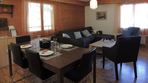 En matplats med ett träbord för fyra personer, en soffa och ett litet bord med stolar.