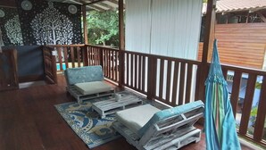 A covered outdoor seating area with wooden furniture and a hammock. - Enjoy the Magic of the Caribbean (Cahuita)