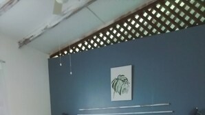 A bedroom with a bed, a headboard, a wooden floor, and a wall with a plant. - Enjoy the Magic of the Caribbean (Cahuita)