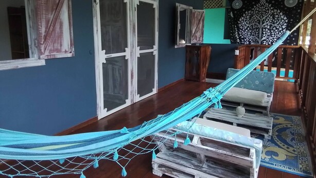 A room with a hammock, wooden furniture, and a patterned tapestry. - Enjoy the Magic of the Caribbean (Cahuita)