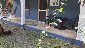Un espacio al aire libre techado con una pared azul, una puerta y dos sillas.