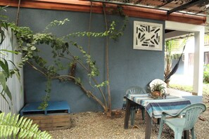 A covered outdoor area with a table and chairs, a bench, and a wall with a geometric design. - Brisas del Caribe Apartment (Cahuita)