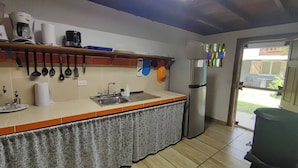 Una cocina con un lavamanos, una cafetera y un refrigerador.