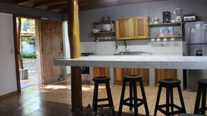 Una cocina con una isla grande, armarios de madera, un refrigerador y taburetes de bar.