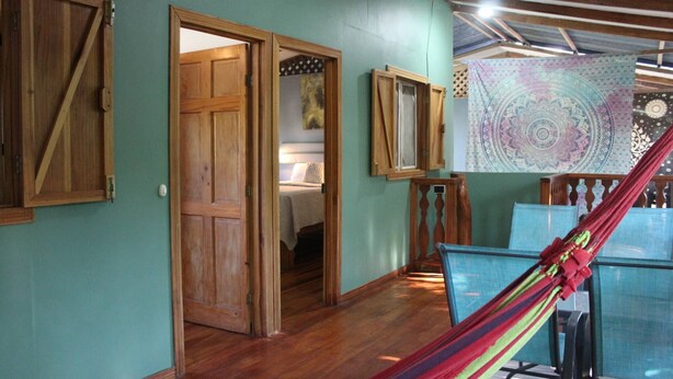 Una habitación con puertas de madera, una hamaca y un tapiz en la pared.