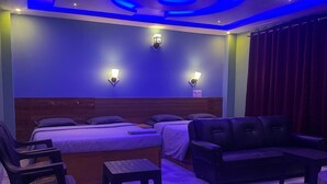 A modern hotel room with a bed, two sofas, a small table, and a chair. - Lahaven Guest House (Shillong)
