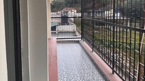 A narrow corridor with a tiled floor leading to a balcony with a metal railing. - Lahaven Guest House (Shillong)