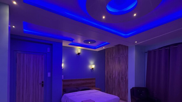 A modern bedroom with a wooden bed, a small table, and a chair. - Lahaven Guest House (Shillong)