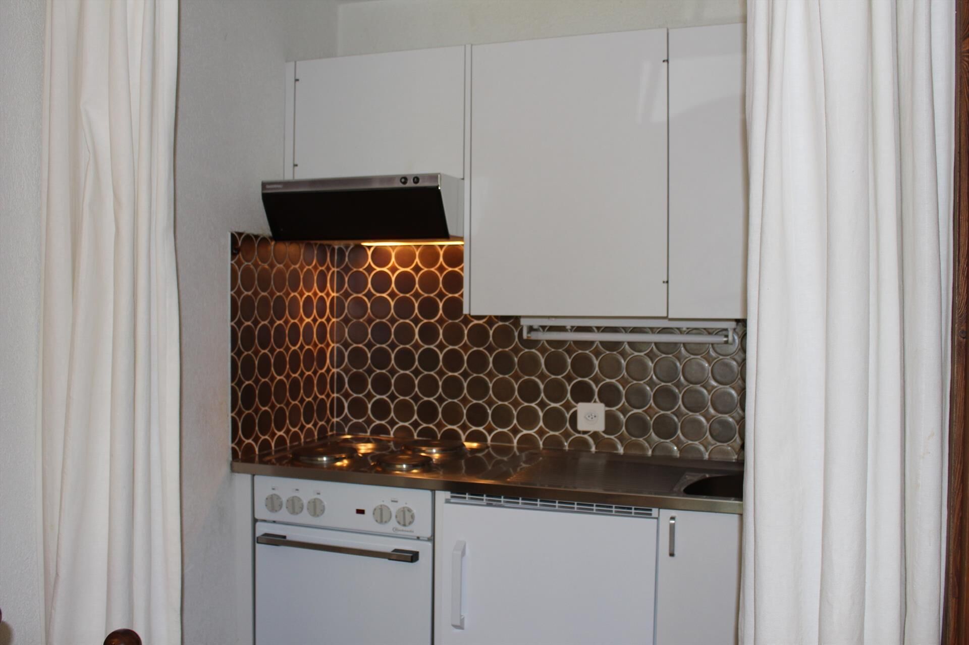 A kitchen with a stove, oven, and a backsplash with circular patterns.
