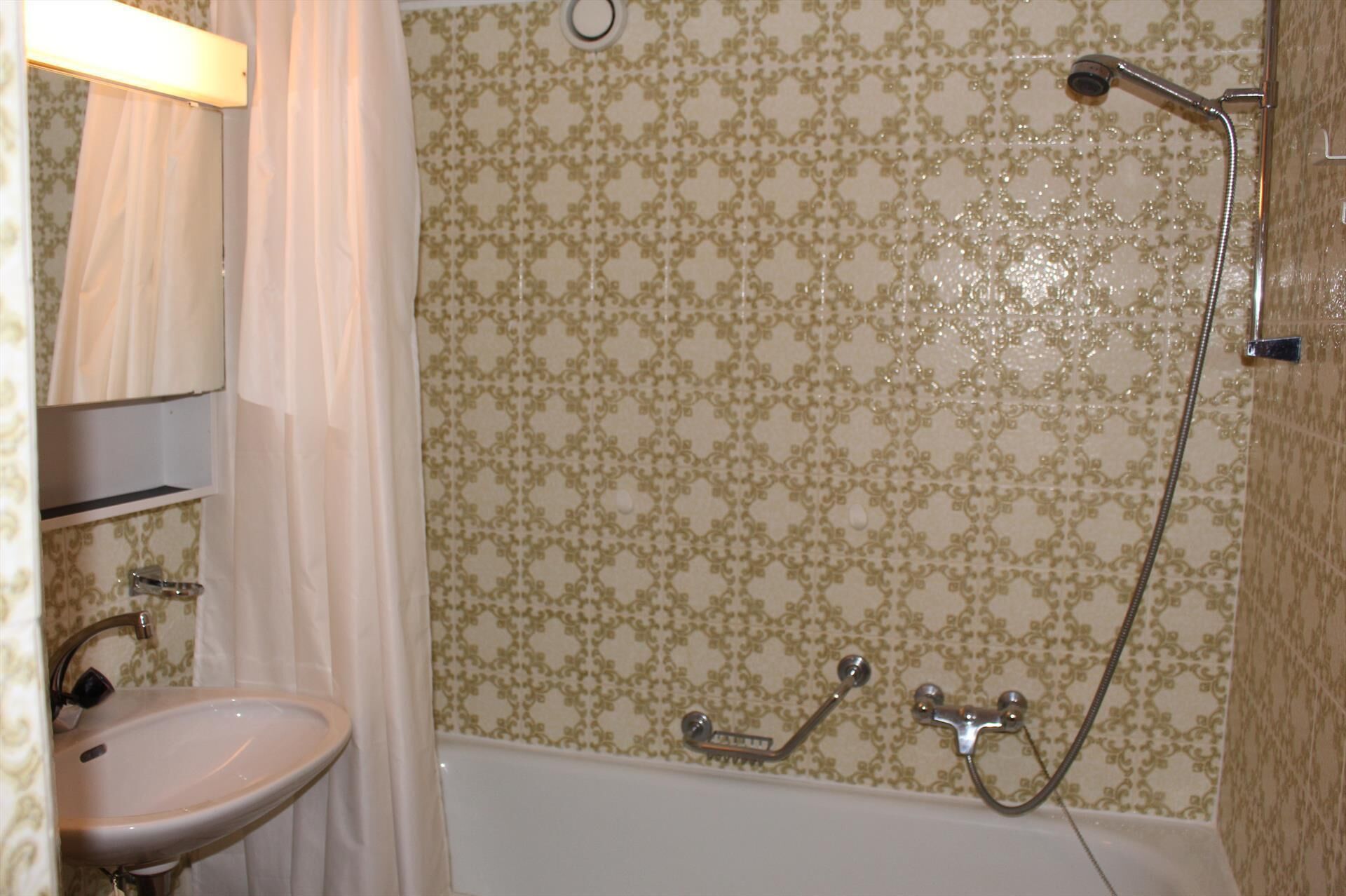 A bathroom with a sink, a shower with a handheld showerhead, and a bathtub.