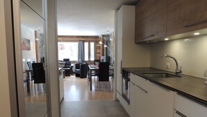 Una cocina moderna con un lavamanos de acero inoxidable, armarios de madera y un comedor con mesa y sillas.
