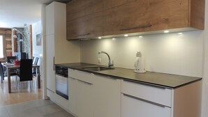 Una cocina moderna con armarios blancos, encimera negra y electrodomésticos de acero inoxidable.