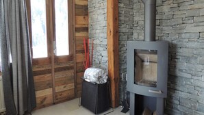 Una habitación con pared de piedra, puerta de madera y chimenea moderna con conducto.