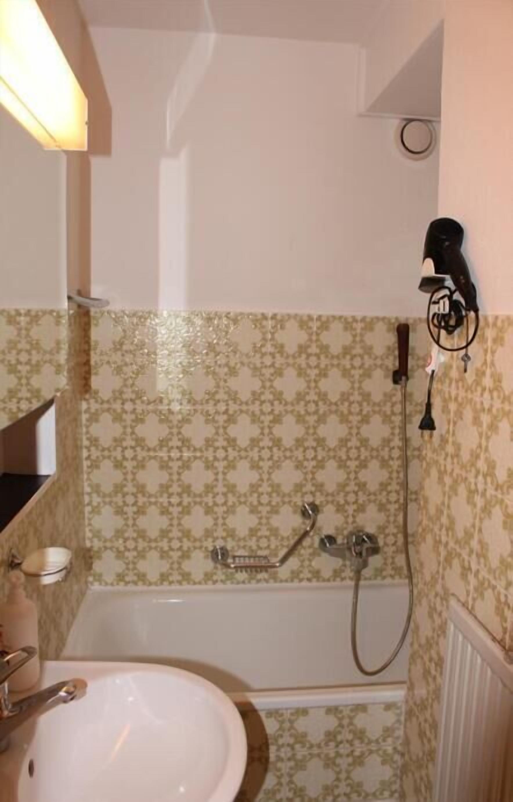 Ein Badezimmer mit Waschbecken, Spiegel, Dusche und fliesenbesetztem Boden.