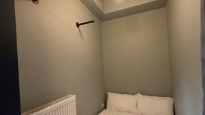 A small, dimly lit room with a single bed, a radiator, and a hanging light fixture. - Luxury 2 5 Bedroom Flat in Southsea (Portsmouth)