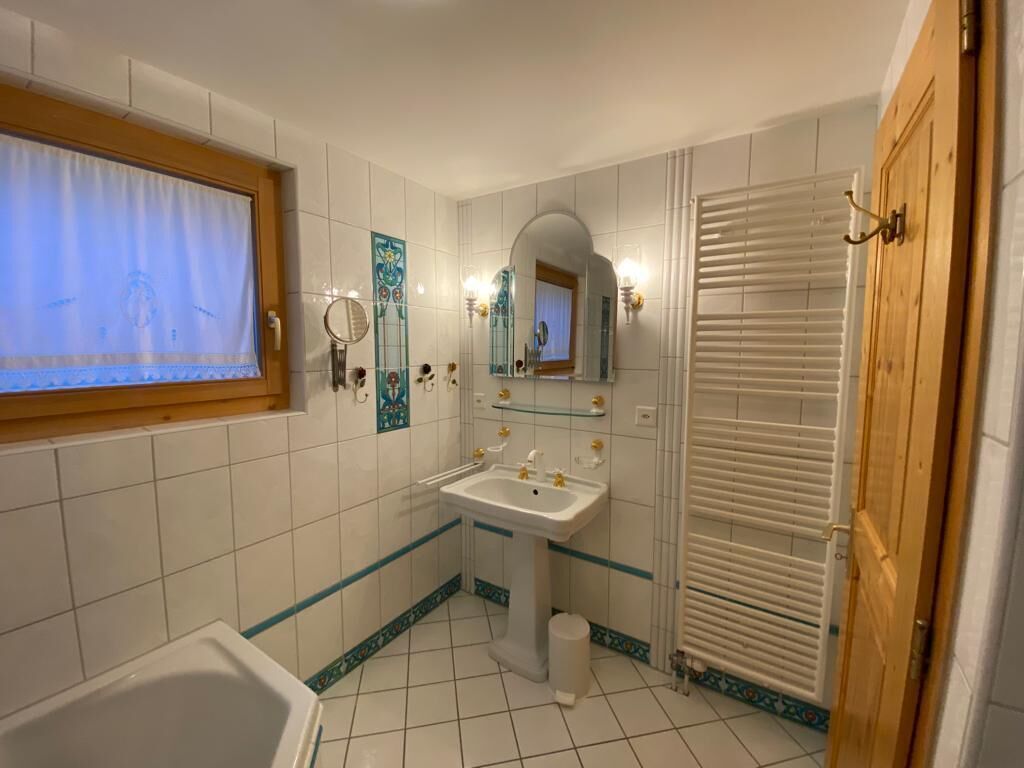 A bathroom with a bathtub, sink, and mirror.