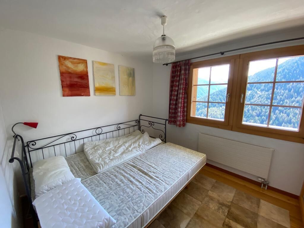 Quarto com cama, janela com vista para montanhas e radiador.