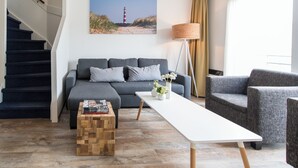 Ein modernes Wohnzimmer mit einem grauen Sofa, einem weißen Couchtisch und einem Holznachttisch.