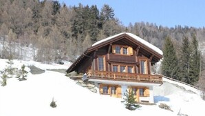 A wooden chalet with a balcony, surrounded by snow and trees. - Very comfortable chalet for 6-8 persons : Living room with fireplace - kitchen with dishwasher, Dolc (Grimentz)