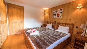 A wooden-paneled room with a bed, two nightstands, and a wall-mounted lamp. - Very comfortable chalet for 6-8 persons : Living room with fireplace - kitchen with dishwasher, Dolc (Grimentz)