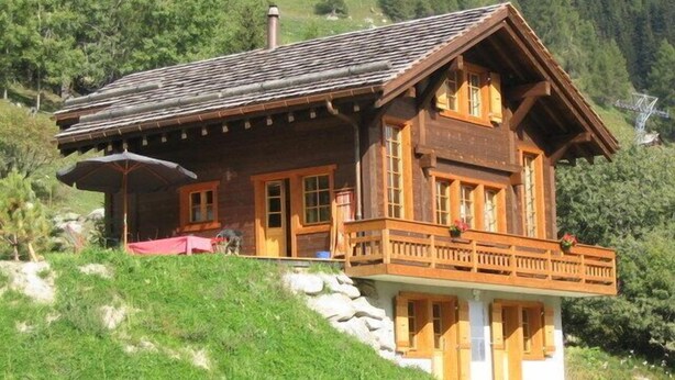 A wooden chalet with a balcony, set on a hillside with a view of a forested mountain. - Very comfortable chalet for 6-8 persons : Living room with fireplace - kitchen with dishwasher, Dolc (Grimentz)