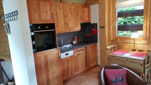 A wooden cabin kitchen with a stove, oven, sink, and wooden cabinets. - Small, very comfortable chalet in the old village for 2 persons : living room with wood-stove - flat (Grimentz)