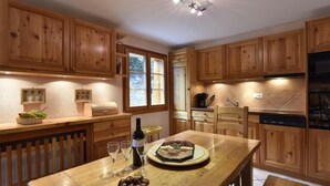 A wooden kitchen with a dining table, wine glasses, and a bottle. - Very comfortable 4 room apartment for 6-7 persons : Living room with fireplace - kitchen with dishwa (Grimentz)