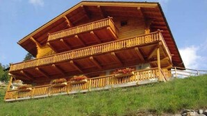 A wooden chalet with a sloped roof, a balcony with railings, and flower boxes on the railing. - Very comfortable 4 room apartment for 6-7 persons : Living room with fireplace - kitchen with dishwa (Grimentz)