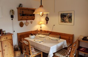 A dining area with a wooden table set for four, a bench, and a wall-mounted clock. - 2-room apartment for 2-3 persons : Living room with sofa-bed - kitchen with dishwasher - 1 room with (Grimentz)