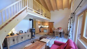 Ein geräumiger Wohnbereich mit einer Holztreppe, einem Esstisch und einem roten Sofa.